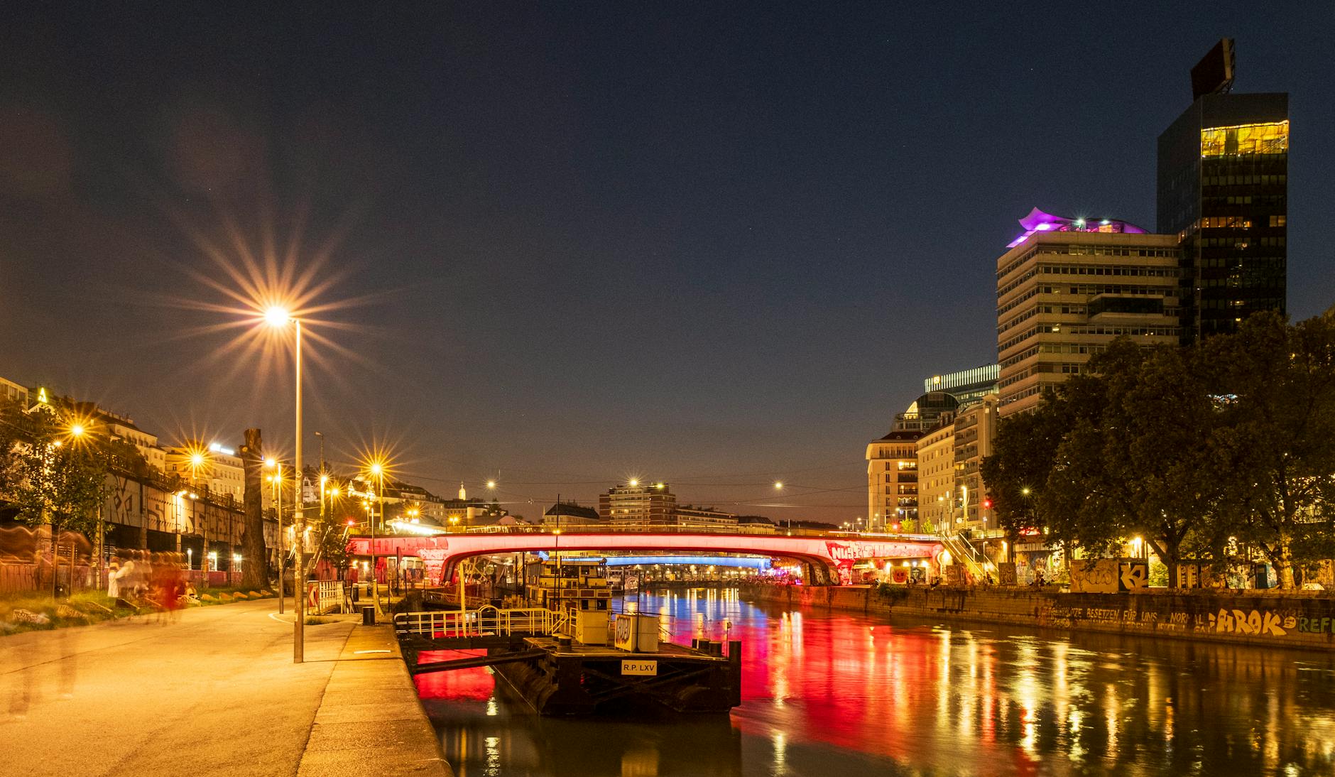 Illuminated Danube Canal in Vienna at night with reflections on water