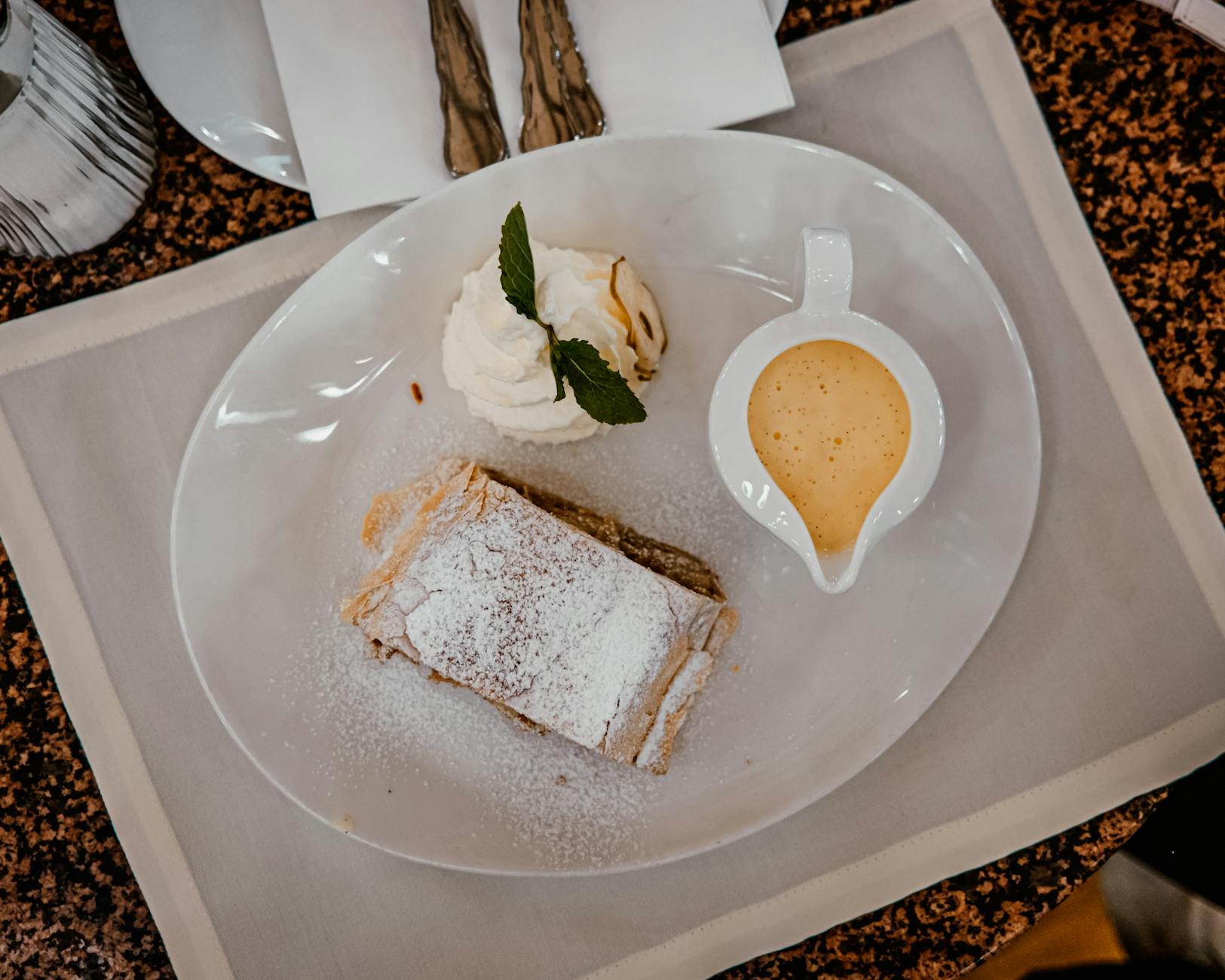 Traditional Viennese apple strudel served with whipped cream and vanilla sauce