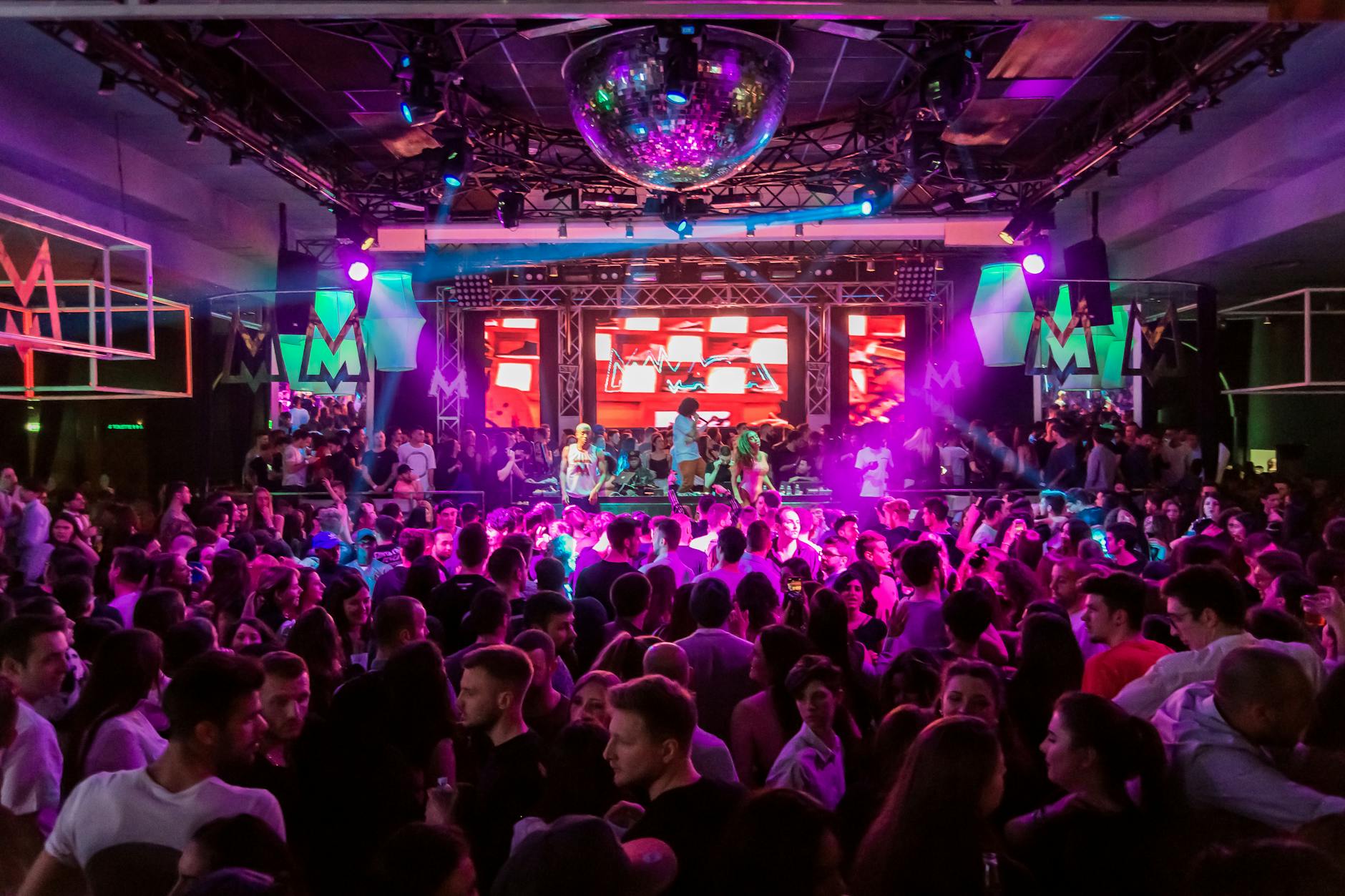 Energetic crowd dancing at a Vienna nightclub with colorful lights