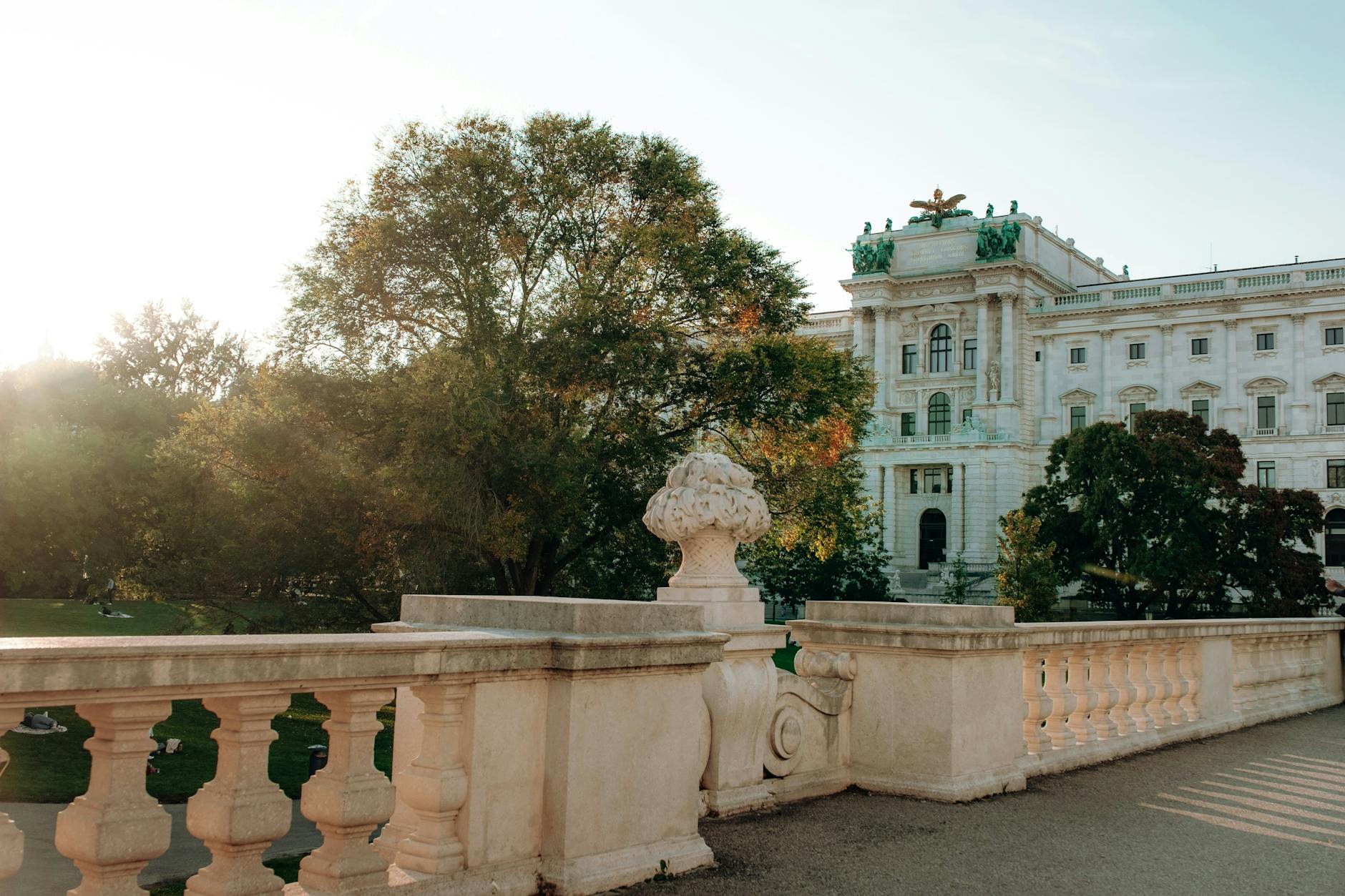 Hofburg Palace in Vienna bathed in sunlight with lush green gardens in the foreground