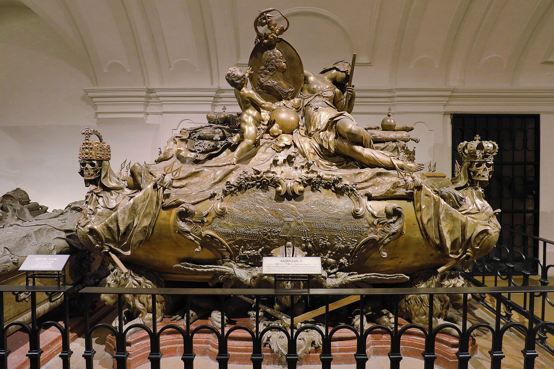 The elaborate bronze sarcophagus of Emperor Karl VI in the Imperial Crypt, flanked by crowned skulls at each corner