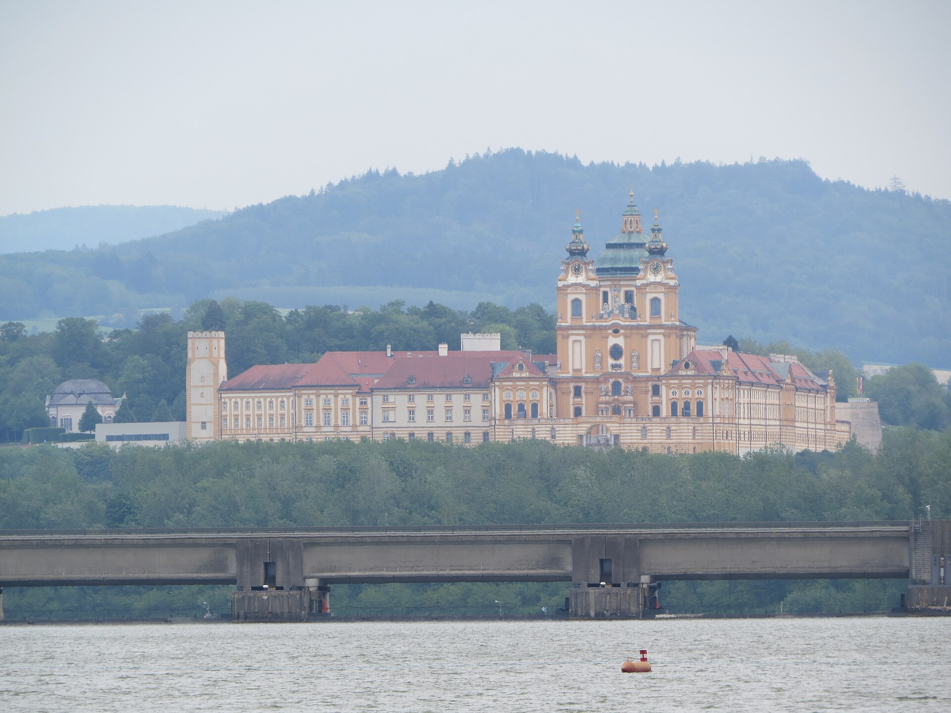 Melk Abbey on its bluff above the Danube, seen from the river with a road bridge in the foreground