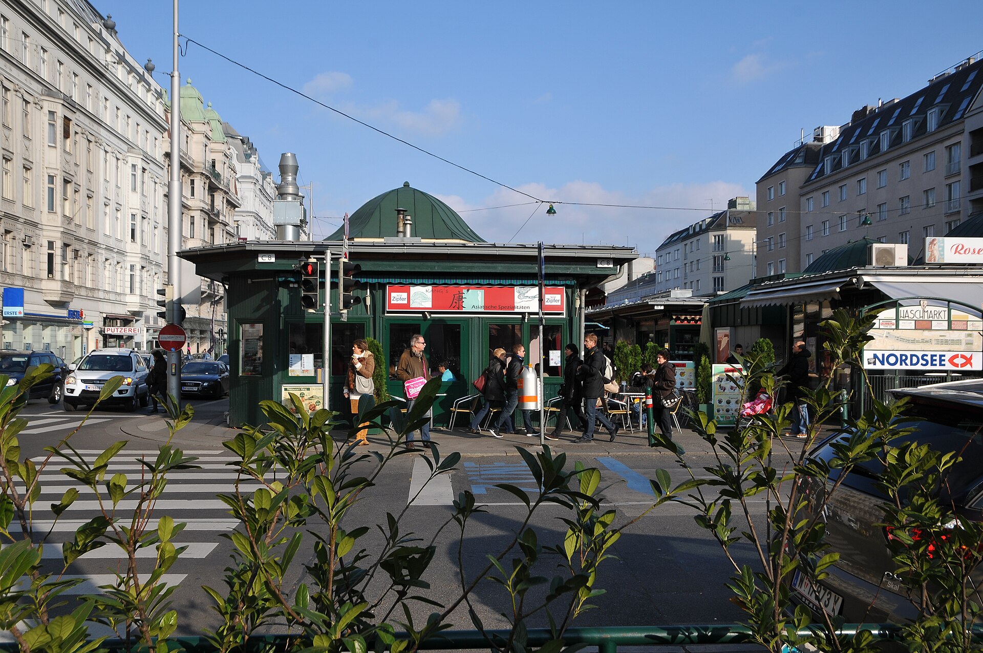 The Naschmarkt in Vienna seen from the street crossing, with green market pavilions and shoppers