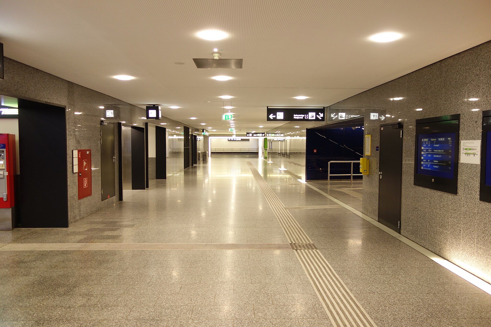 The concourse of the railway station beneath Vienna Airport with departure screens and signs to the platforms