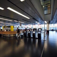 The Terminal 3 check-in hall at Vienna Airport with self-service kiosks and large A B C D gate signage above the entrance to the piers