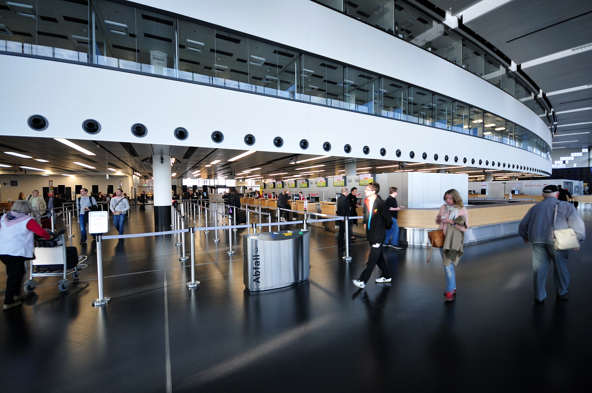 The check-in area of Terminal 3 at Vienna Airport with passengers walking through the landside hall