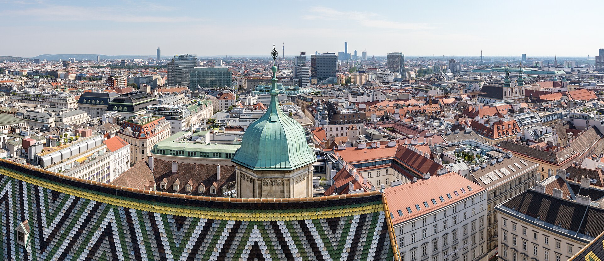 A panoramic view over the rooftops of central Vienna from the south tower of Stephansdom, with the patterned tiled roof in the foreground