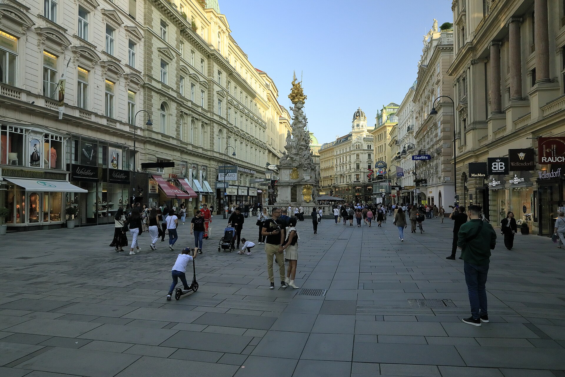 The Graben in Vienna in evening light with the Plague Column and shoppers walking on the wide pedestrianised street
